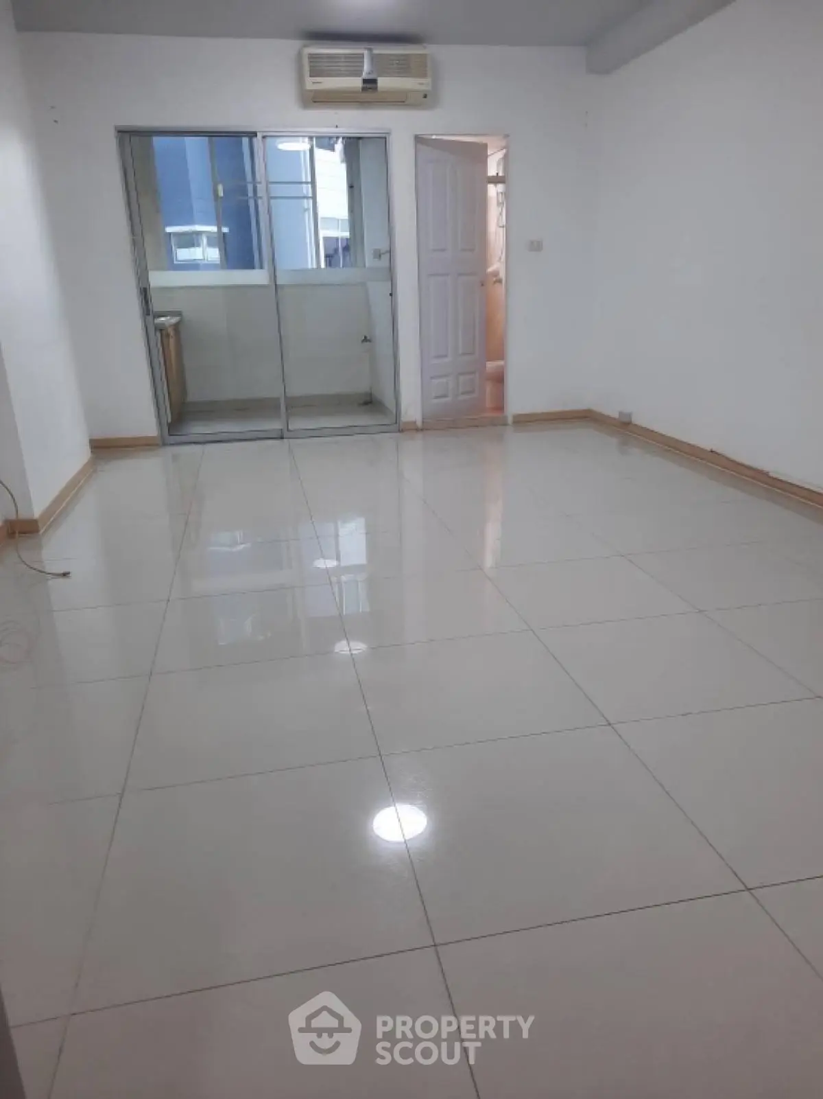 Spacious empty room with glossy tiled floor and air conditioning unit.