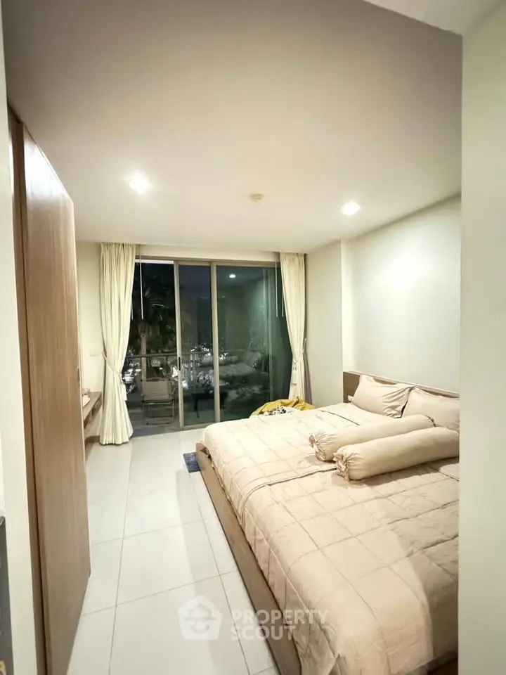 Spacious bedroom with large bed and balcony access in modern apartment