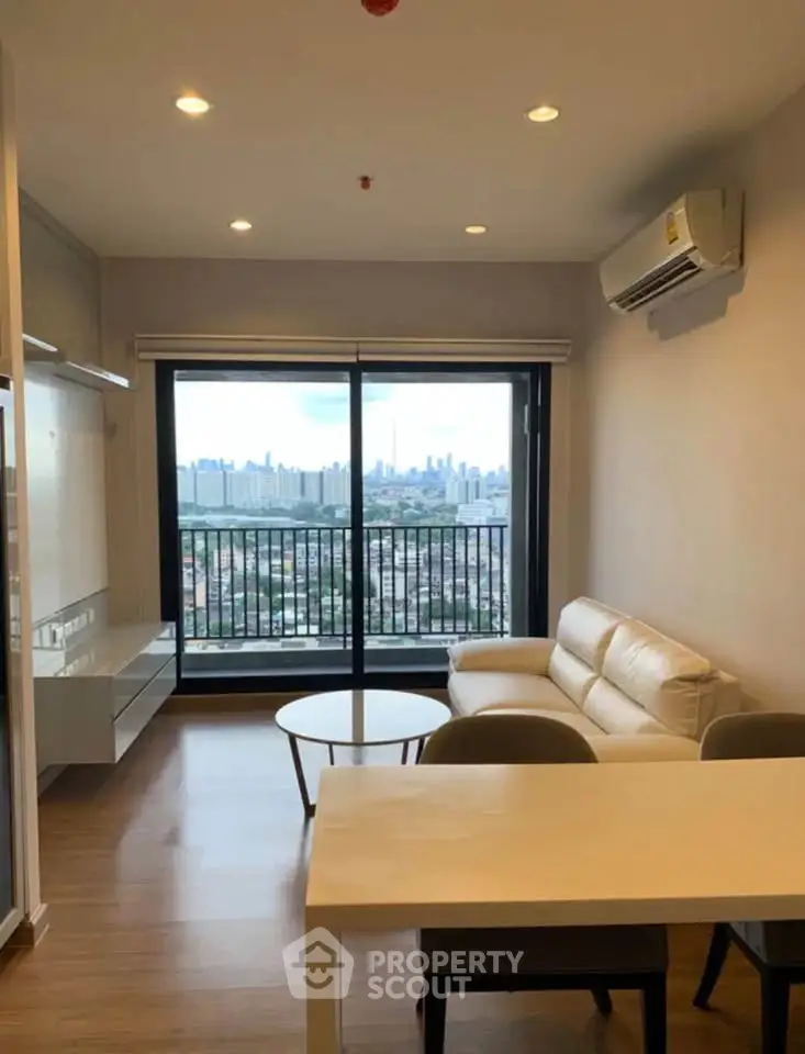 Modern living room with city view, featuring sleek furniture and large windows for natural light.