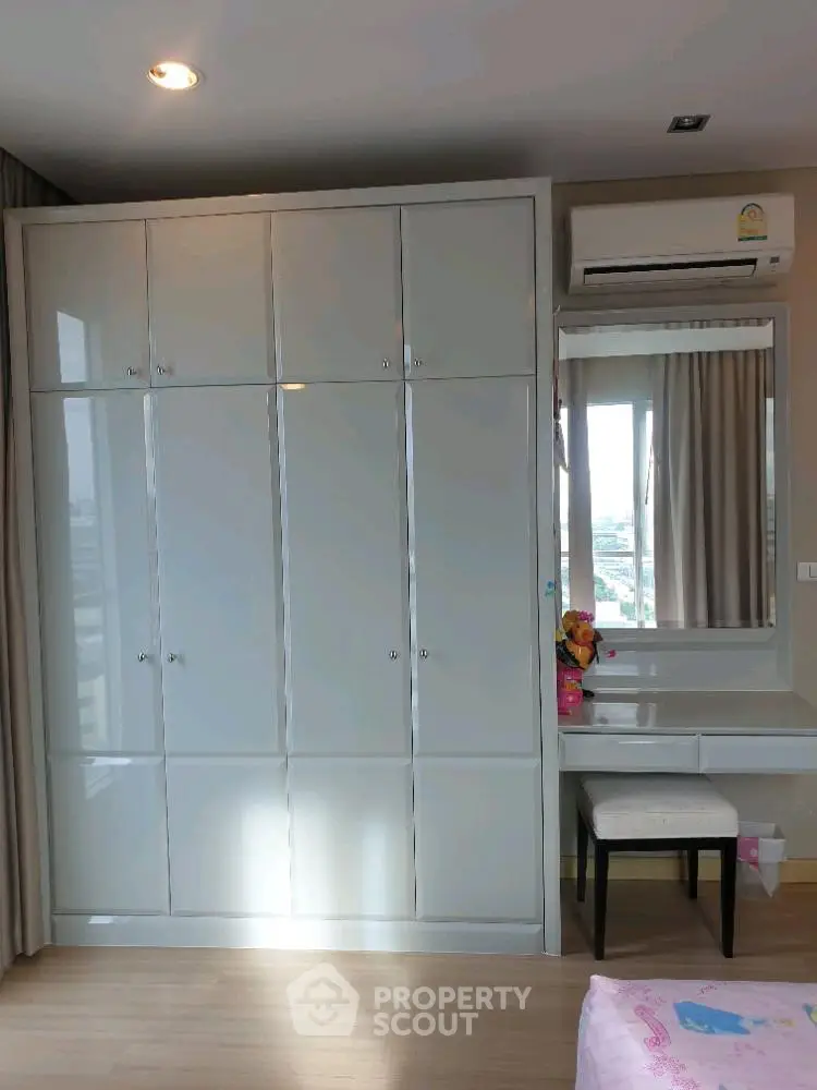 Spacious bedroom with built-in wardrobe and vanity area, featuring modern design and ample storage.