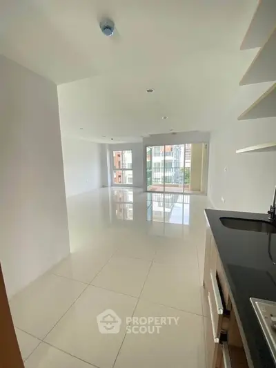 Spacious open-plan living area with modern kitchen and large windows in a contemporary apartment.