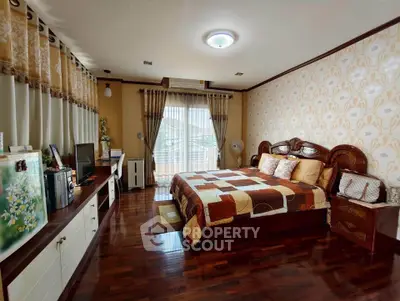Spacious bedroom with elegant decor and hardwood flooring, featuring a large bed and ample natural light.