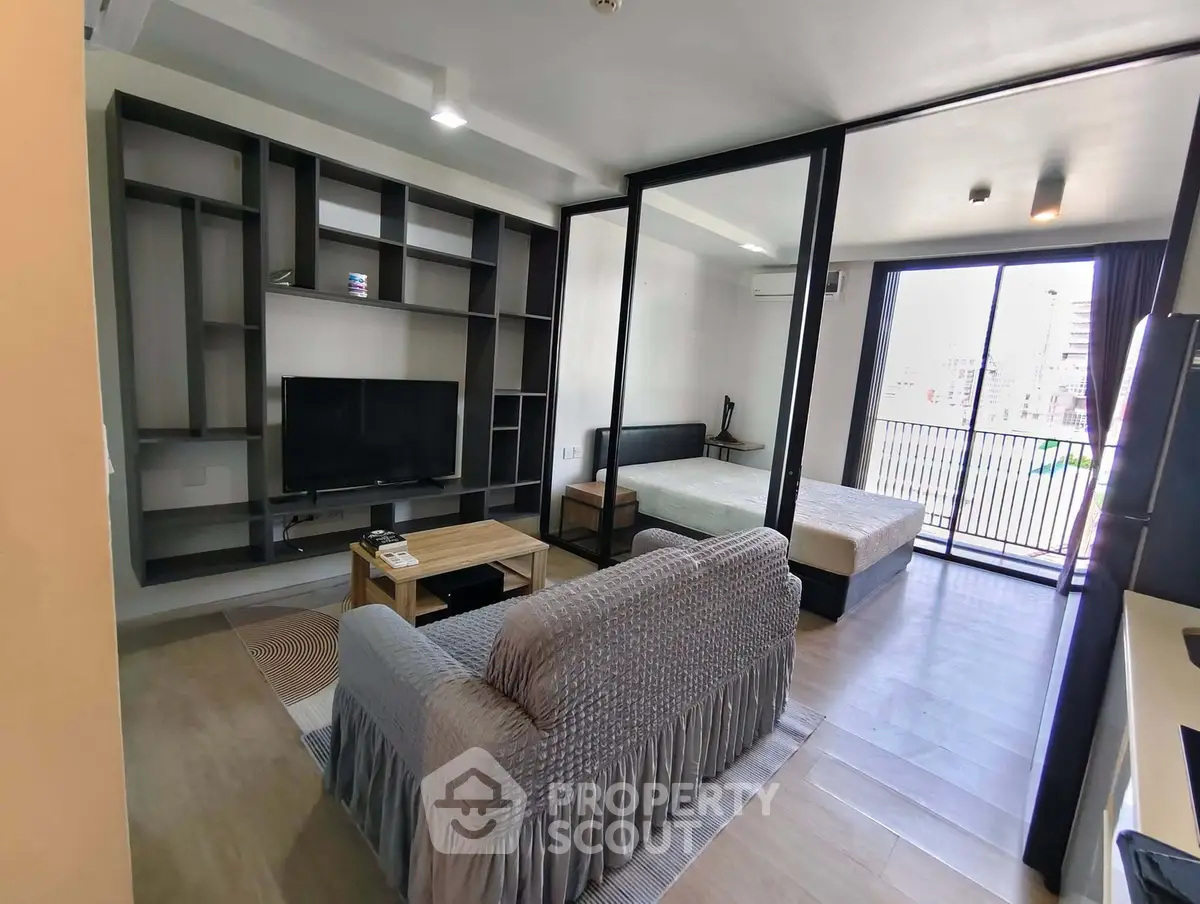 Modern open-plan living room with TV and balcony access in stylish apartment