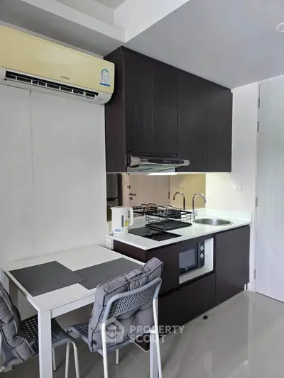 Modern compact kitchen with sleek cabinetry and dining area in a stylish apartment.