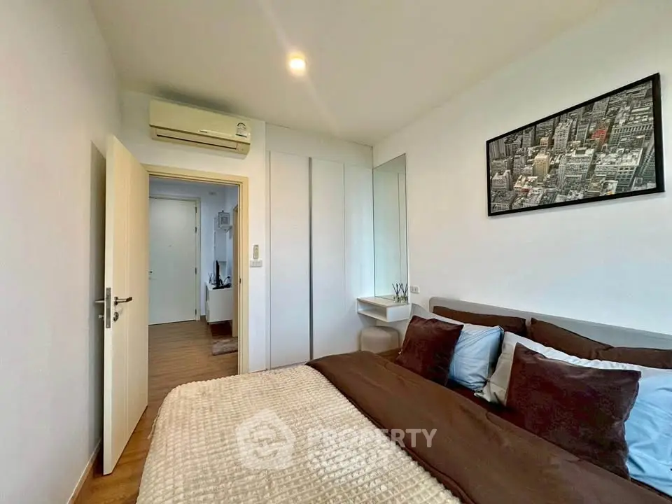 Modern bedroom with cozy bedding and wall art, featuring a sleek air conditioning unit and minimalist decor.