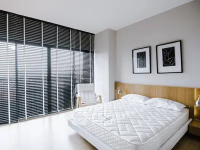 Modern bedroom with large windows and stylish decor, featuring a comfortable bed and contemporary artwork.
