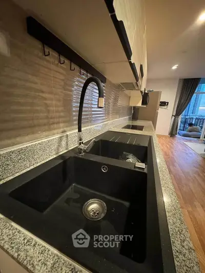 Modern kitchen with sleek black sink and granite countertops, open layout design, and stylish fixtures.