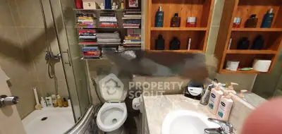 Cozy bathroom with shower, toilet, and ample shelving for storage.