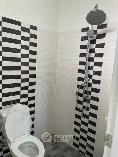 Modern bathroom with stylish black and white tile design and sleek shower fixture.