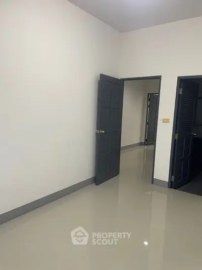 Minimalist empty room with glossy floor and dark doors, perfect for customization.