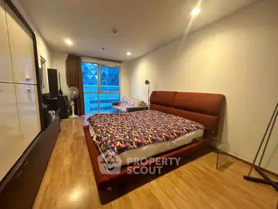 Spacious bedroom with modern decor and large window offering natural light.