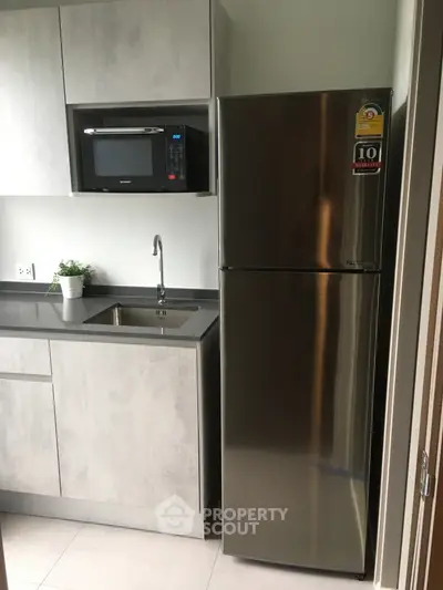 Modern kitchen with sleek stainless steel fridge and built-in microwave, perfect for urban living.