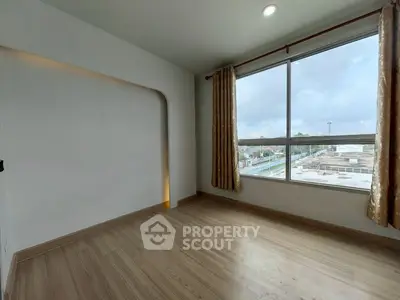 Spacious empty room with large window and wooden flooring