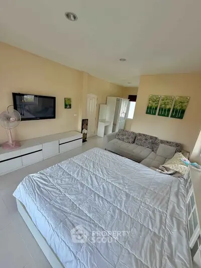 Spacious bedroom with modern decor and large bed, featuring a wall-mounted TV and cozy seating area.