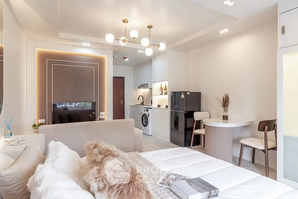 Modern open-plan living room with cozy decor and kitchen appliances.