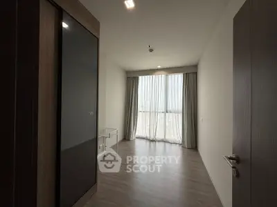 Spacious empty room with large window and wooden flooring, perfect for customization.