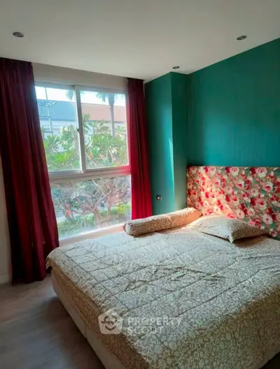 Cozy bedroom with floral headboard and large window overlooking greenery.