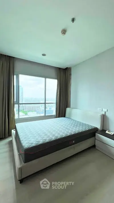 Spacious bedroom with large window offering stunning city views, featuring a comfortable bed and modern decor.