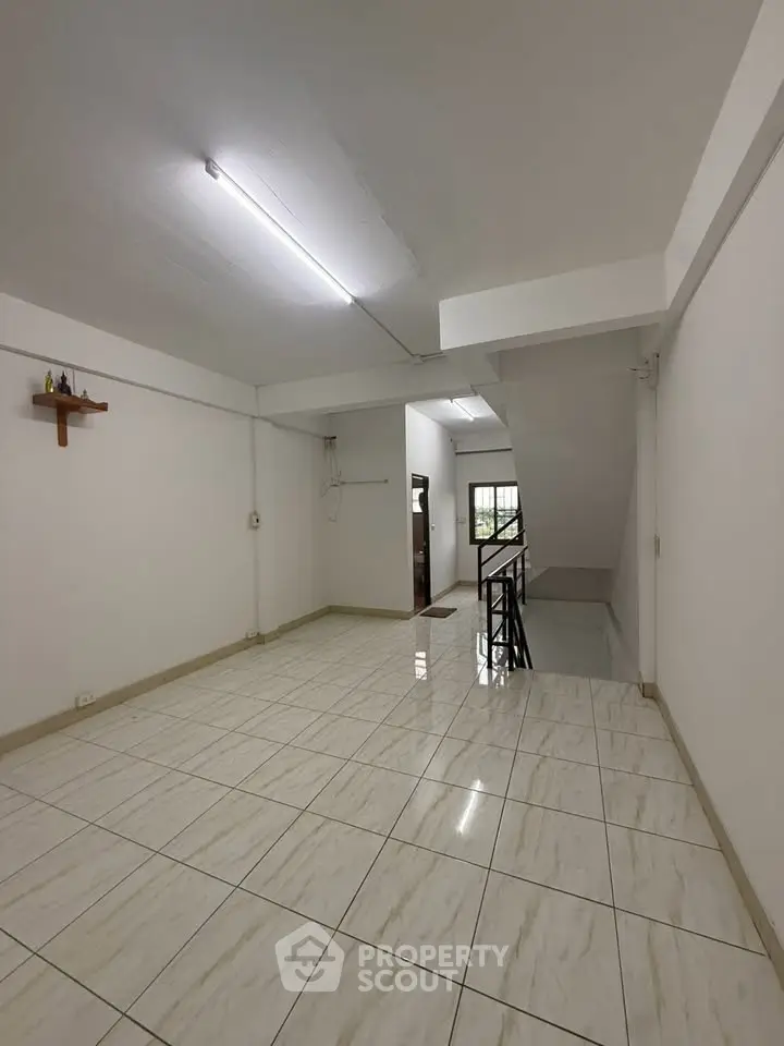 Spacious tiled room with staircase and natural light, ideal for versatile living space.
