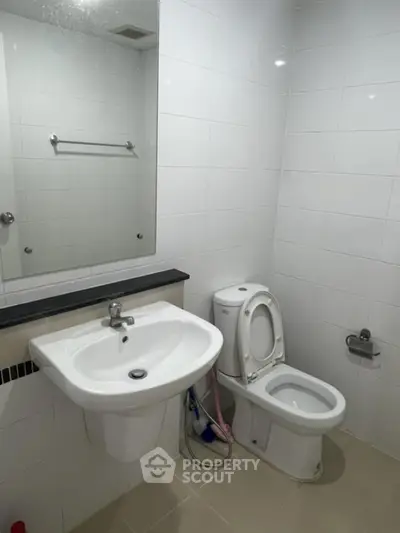 Modern bathroom with white tiles and sleek fixtures in real estate property