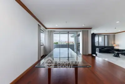 Spacious modern living room with glass table and panoramic city view.