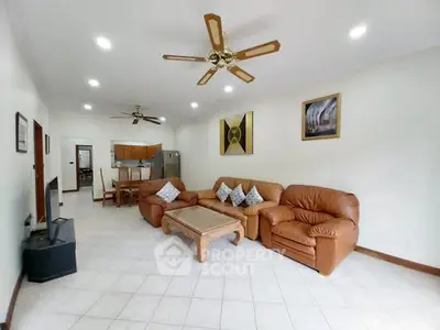 Spacious living room with leather sofas and ceiling fans in a modern apartment.