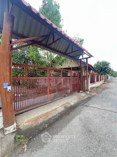Charming rustic entrance with wooden gate and covered driveway in serene neighborhood.