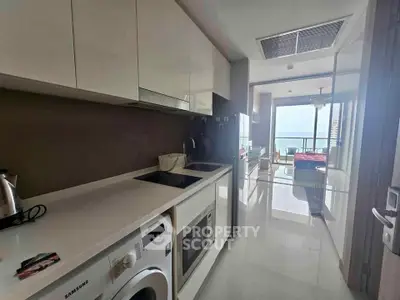 Modern kitchen with sleek appliances and open layout leading to a bright living area with a view.