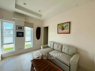 Cozy living room with modern sofa and wall art, bright natural light from large windows.