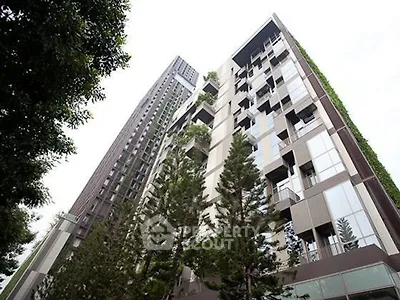 Modern high-rise building with lush greenery and sleek architecture in urban setting.