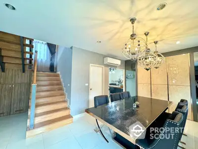 Modern dining area with elegant lighting and staircase in a stylish home interior.