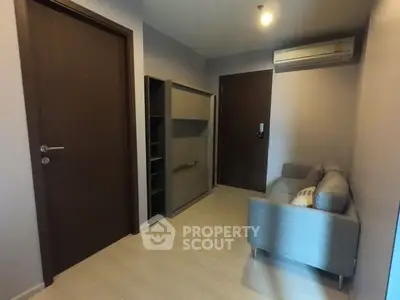 Cozy small living room with modern sofa and air conditioning, perfect for compact living spaces.