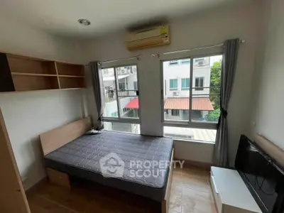 Cozy bedroom with large windows and modern furnishings in a bright apartment.