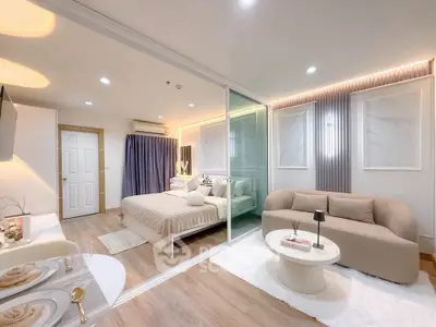 Modern studio apartment with elegant decor, featuring a cozy living area and stylish bedroom separated by glass.