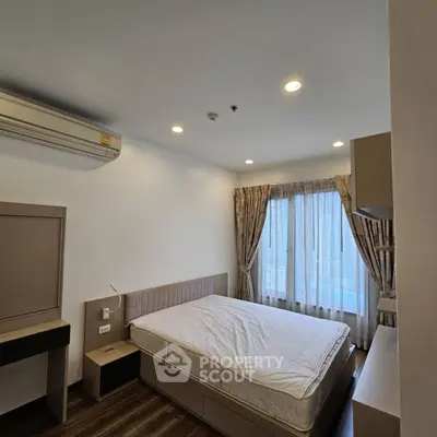 Spacious bedroom with modern decor and natural light from large window.