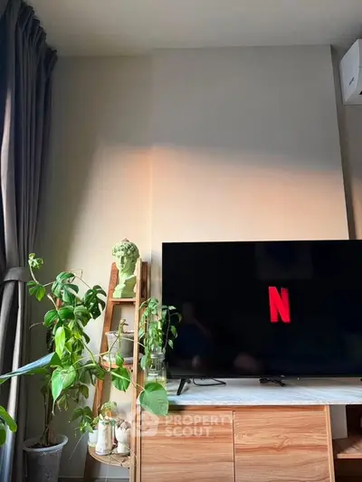Cozy living room with modern TV setup and lush indoor plants, perfect for relaxation and entertainment.