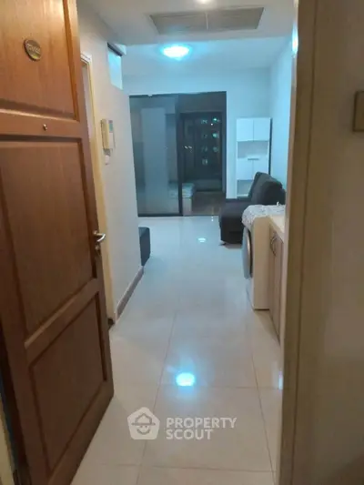 Cozy apartment entrance leading to a modern living area with sleek furniture and washing machine.