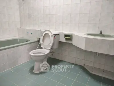 Spacious bathroom with bathtub and modern fixtures in a tiled setting.