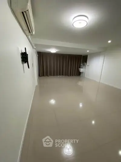 Spacious empty living room with glossy tiled floors and modern lighting, ready for customization.