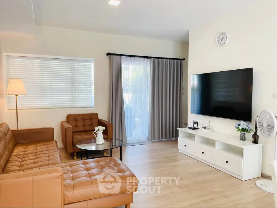 Modern living room with leather sofa and large TV, bright and inviting space.