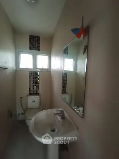 Cozy bathroom with sink, mirror, and natural light from window.