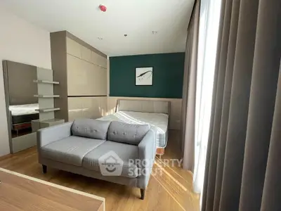 Modern bedroom with stylish decor and natural light, featuring a cozy sofa and elegant furnishings.