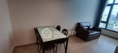 Modern living room with dining area and city view, featuring sleek furniture and large windows.