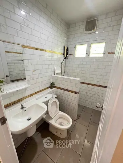 Compact bathroom with modern white tiles and essential fixtures