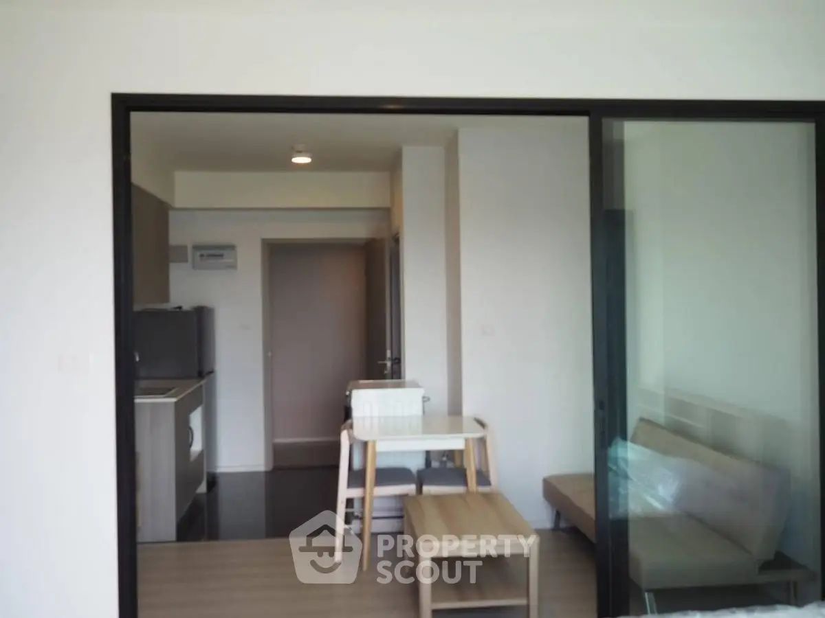 Modern apartment interior with open layout featuring kitchen and living area, sleek furniture, and natural light.