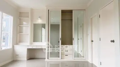 Spacious bedroom with built-in wardrobe and vanity desk, featuring sleek modern design and ample natural light.