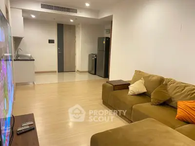 Spacious living room with modern kitchen and cozy sofa in open layout apartment.