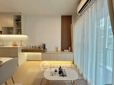 Modern living room with open kitchen, stylish decor, and large windows for natural light.