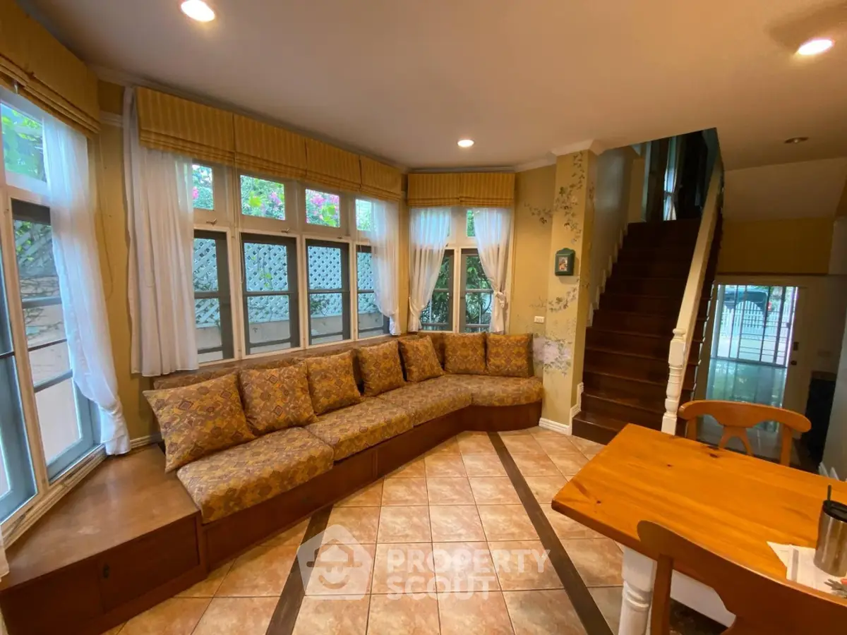 Charming living room with cozy built-in seating and large windows offering natural light.