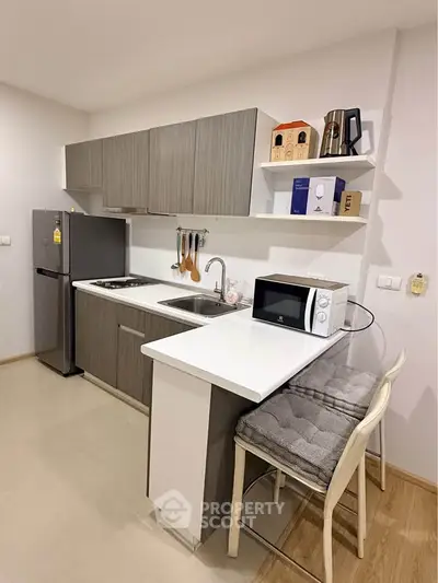 Modern kitchen with sleek cabinetry, stainless steel fridge, and cozy breakfast bar seating.
